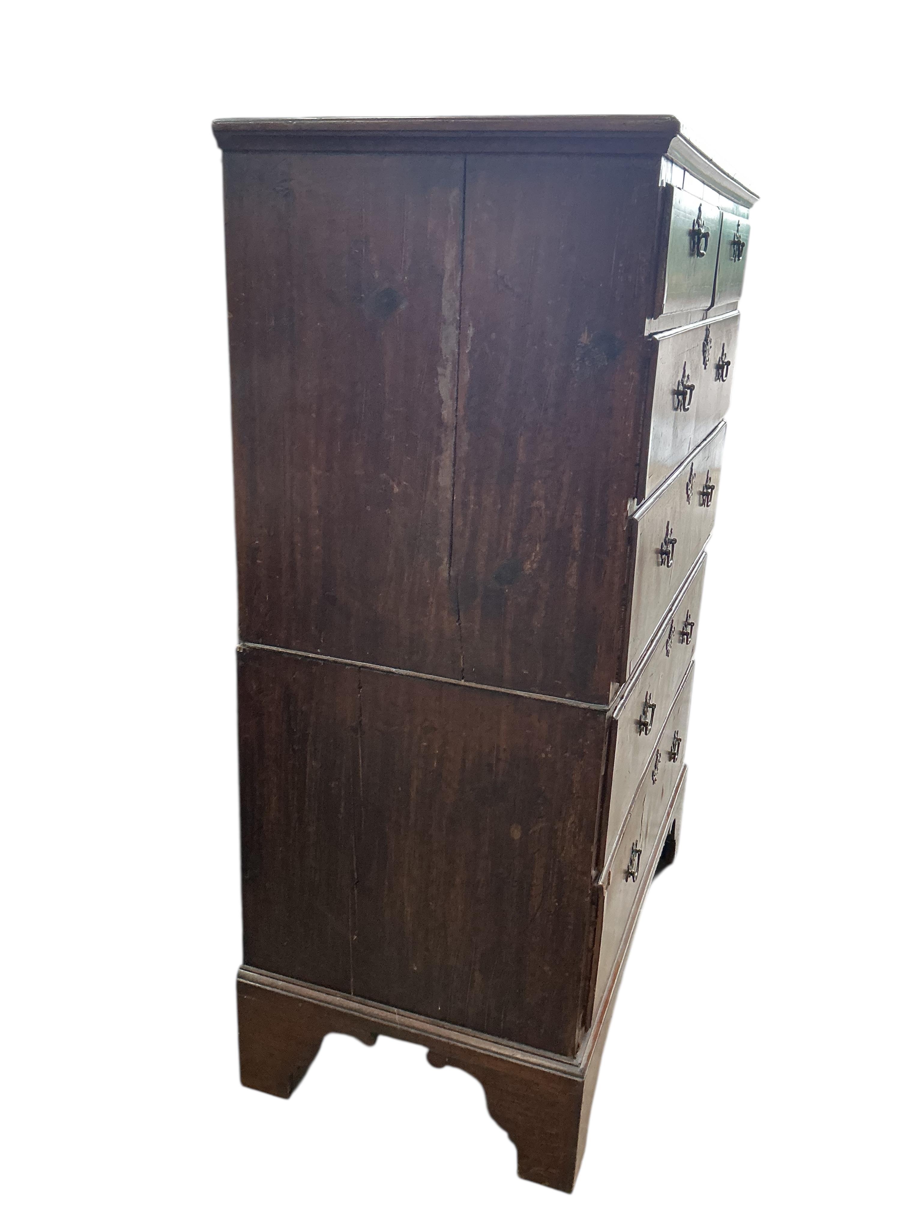 An early 18th century feather banded walnut and pine two section chest of drawers, on later bracket feet and with losses, width 96cm, depth 52cm, height 135cm